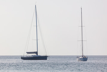 Two sailboats are in the water, one is larger than the other