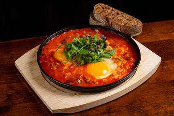 Delicious shakshuka with poached eggs in spicy tomato sauce and herbs, accompanied by rustic bread