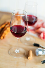 Naklejka premium Two elegant glasses filled with deep red wine rest on a rustic wooden table, inviting relaxation