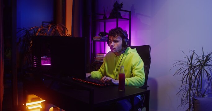 Young man in headphones playing video games on the computer