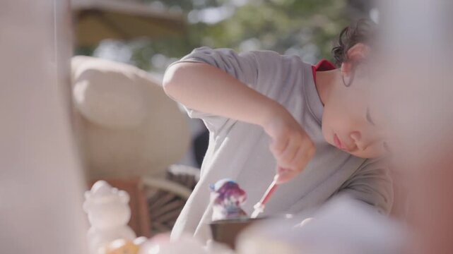 Child carefully coloring a plaster sculpture with a paintbrush, enjoying a creative DIY craft project that develops imagination, focus, artistic expression, fine motor skills, and creativity.