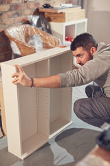Man working and assembling furniture in a new apartment.