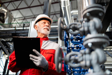Senior engineer inspecting oil refinery pipelines