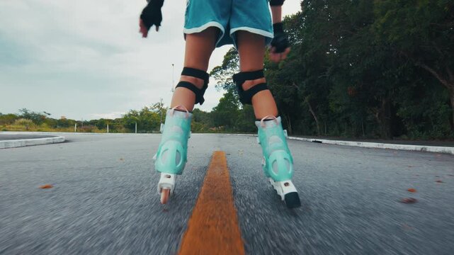 Girl learns roller skating on the road in the park and does her first attempts in the sport