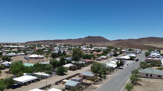 The camera rises from street level to reveal the Small Tourist town of Williston in the Karoo's dry, brown landscape, all around the town. 4K Aerial Video.