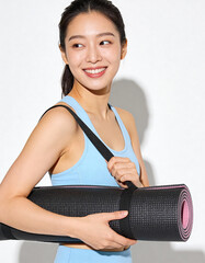 Smiling young woman holding a yoga mat in her hands and looking at the camera