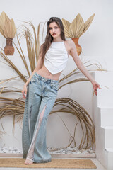 Fashion portrait of a young beautiful brunette girl in blue jeans