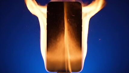 A closeup shot of a modern smartphone engulfed in intense orange flames against a vibrant blue background symbolizing device malfunction overheating and potential technological hazards or product fai.