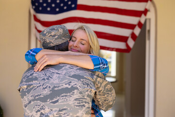 Happy blond caucasian woman hugging army soldier on his return home at the entrance