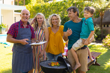 Portrait of smiling caucasian three generational family barbecuing together in the garden