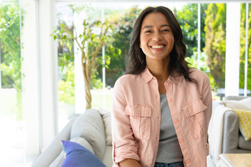 Portrait of cheerful young beautiful african american woman sitting in living room at home