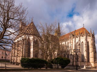 Fototapeta premium Rear view of St. Michael Chapel in Košice, Slovakia. Gothic stone chapel with tiled roof, bare trees and cloudy winter sky in historic city center.