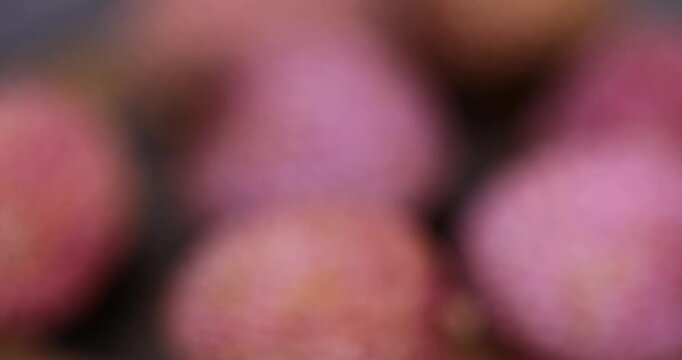 ripe red lychees scattered on a wooden table, red-skinned lychee fruits,rough textured lychee peel closeup