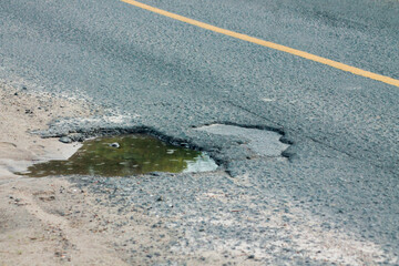 Old asphalt road with dangerously damaged asphalt that has potholes dangerous for the transit of motor vehicles