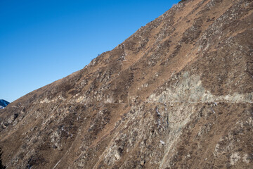 High altitude mountain landscape in winter. Perspective of a snowy road leading to rocky peaks and summits