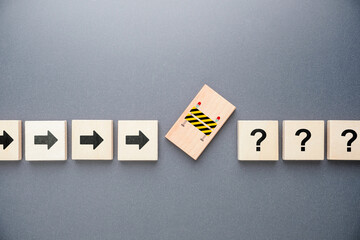 Wooden arrow blocks moving forward toward a sudden obstacle and question marks, representing unexpected problems, delays, and uncertainty concept in business process, planning