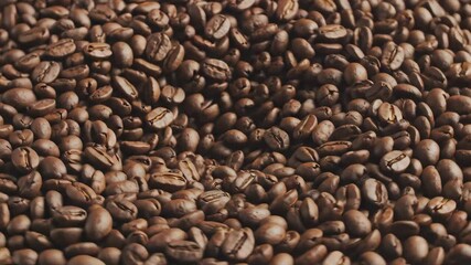 A rich and aromatic closeup view of freshly roasted coffee beans showcasing their varied textures and deep brown hues perfect for illustrating the essence of a morning brew or the journey from bean t.