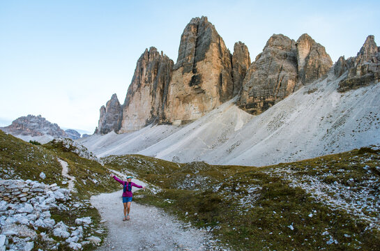 Hiker walks along a scenic mountain trail with dramatic peaks