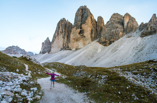 Hiker walks along a scenic mountain trail with dramatic peaks