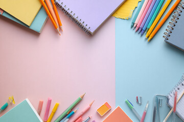 Colorful school supplies and notebooks arranged on pastel pink and blue background