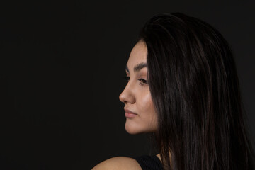 A woman with black hair wakes up in the morning in a white blanket and catches the rays of the sun. The portrait is creative, with brown eyes. High quality photo