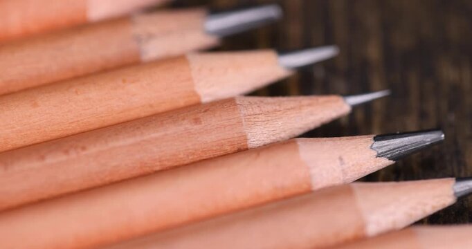 a group of wooden pencils with a black lead on a black board , stacked pencils made of wood and a lead made of graphite