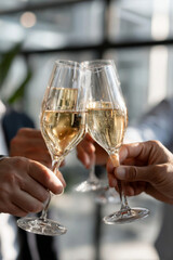 Close-up of coworkers toasting with glasses in a modern office setting, capturing the essence of celebration and teamwork in a soft-lit environment