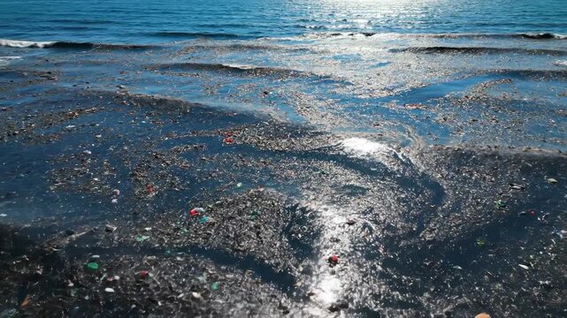 Vast ocean surface covered with fragmented microplastic pollution, sunlight glinting off swirling debris