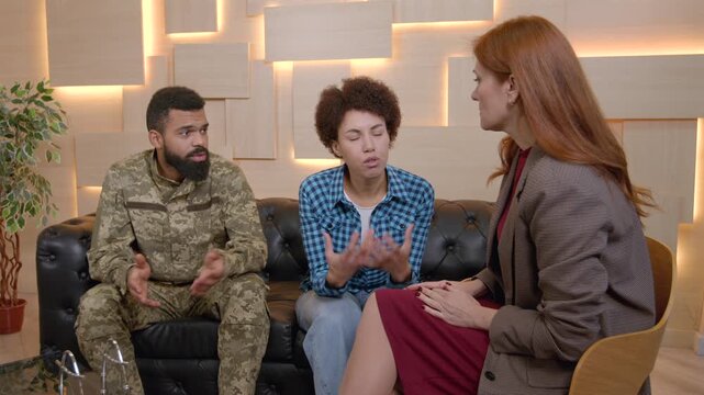 African American male army soldier in military uniform and pretty black woman trying to find solution of problems and common points, sharing about relationship difficulties with female counselor.