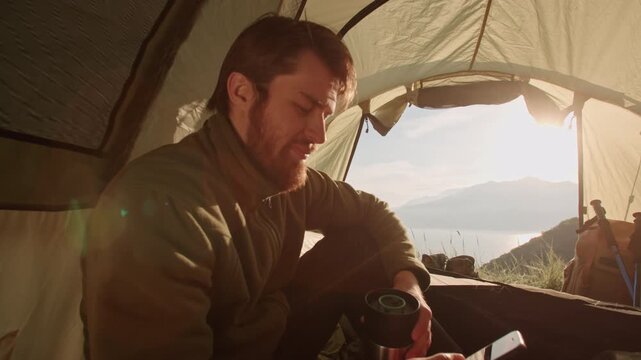 Man sitting cross legged inside tent studying map under sunrise glow concept of planning freedom inspiration curiosity and mindful connection with outdoor exploration