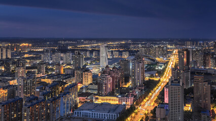 Obraz premium Illuminated Urban Cityscape at Dusk with Glowing Streets and Warm Building Lights