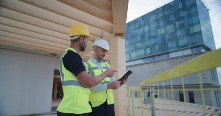 Two Male Engineers Stand on an Commercial Residential Floor, Using Digital Blueprints on a tablet, Real Estate Development. Modern Building Project in an Urban Business District.