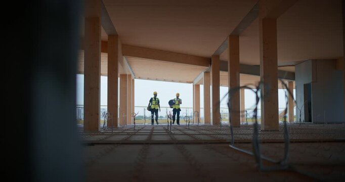 Two Male Engineers Working on Electric Infrastructure of Building Under Construction, Positioning Equipment and Reviewing Safety Precautions, Interior Fit‑out,  Real Estate Development 