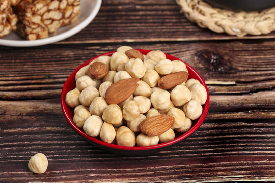 Roasted Hazelnuts and Almonds in Red Bowl on Wood