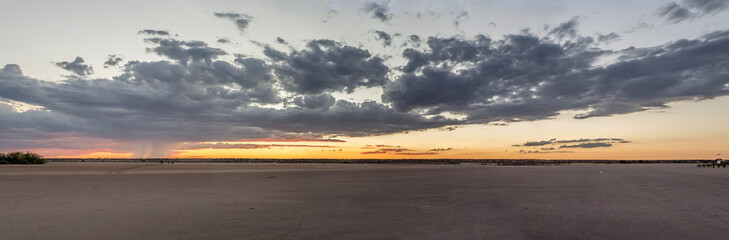 rain showers and clouds in red sky over pan airfield at sunset, Bitterwasser, Namibia
