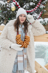 Winter portrait of a young beautiful brunette girl in an eco fur coat