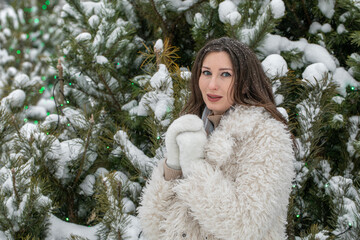 Winter portrait of a young beautiful brunette girl in an eco fur coat
