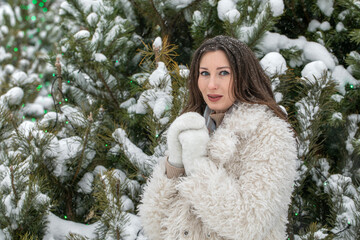 Winter portrait of a young beautiful brunette girl in an eco fur coat