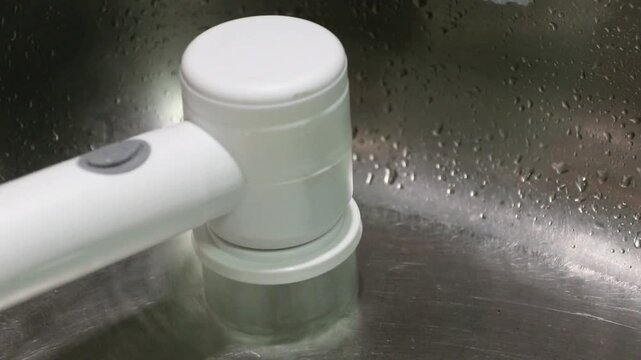 White cleaning brush handle with water droplets sink for kitchen hygiene using faucet sprayer and modern sink faucet extender