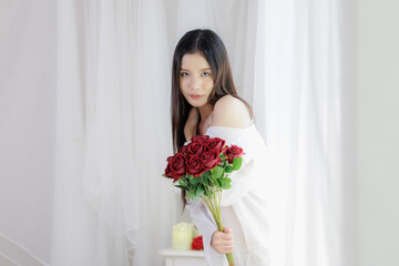 Beautiful Asian woman holding red rose bouquet looking at camera seductive eyes
