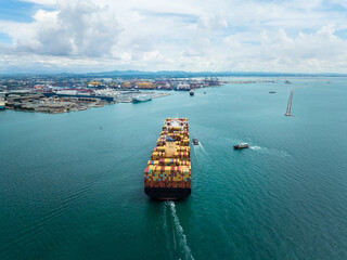 Aerial back view of cargo container ship sailing to harbor for global business logistics and international import export trade transportation industry.