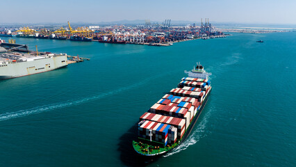 Aerial wide view of large cargo ship approaching industrial port terminal for global business logistics and international import export trade transportation industry.
