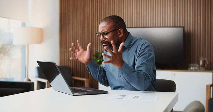 Angry, black man and accountant with laptop for project deadline or bad investment in office. Frustrated, male person or analyst with computer or paperwork for financial crisis, debt or bankruptcy