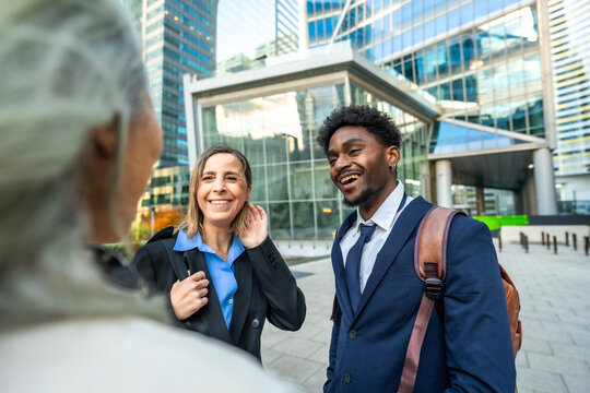 Diverse business professionals having cheerful conversation outdoors in city