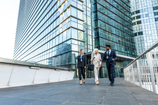 Diverse business team walking and discussing outside modern office building