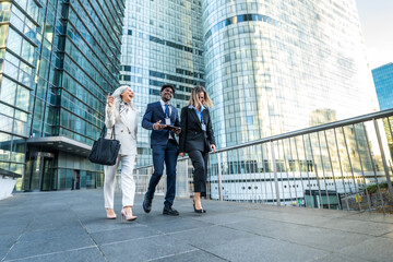 Obraz premium Diverse business team walking, smiling, and discussing outdoors