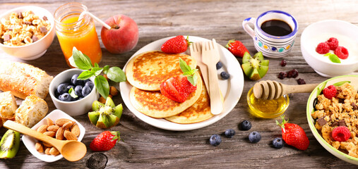 assortment of healthy food breakfast with pancakes, fresh fruits, coffee cup and granola