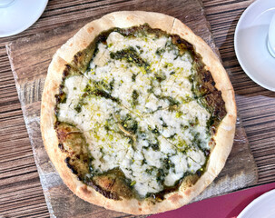 Manakish flatbread with melted cheese pistachio topping on wooden board. Middle Eastern cuisine.