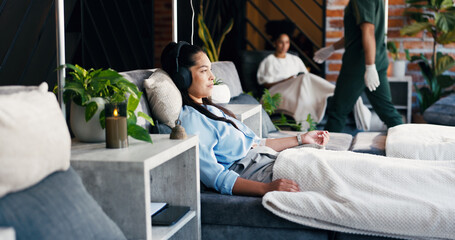 Woman, relax and headphones in drip lounge, healthcare and listening to music for medical treatment. Clinic, recovery and person with tech for audio, immune system boost and iv nutrients for wellness