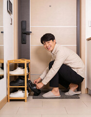 Smiling asian man standing in front of the door with shoes